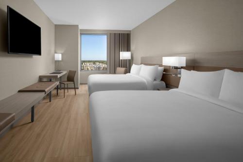 Cette chambre comprend deux lits et une télévision. dans l'établissement AC Hotel by Marriott Miami Dadeland, à Miami