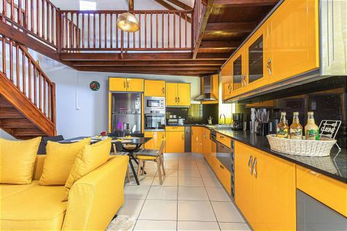 a kitchen with yellow cabinets and a yellow couch at Villa paradisiaque à Pointe-Noire avec piscine privée in Pointe-Noire