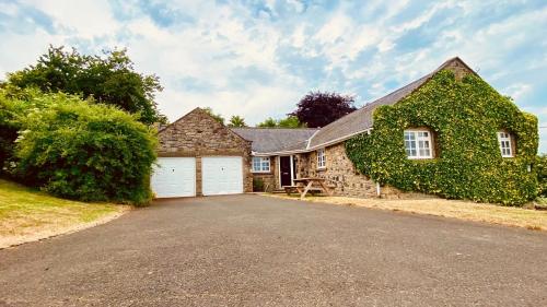 a large stone house with a garage at Coquet View in Rothbury