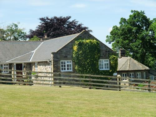 an old stone house with a wooden fence at Coquet View in Rothbury