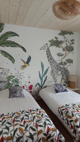 um quarto com duas camas e um mural de uma girafa em LE NID DES PLANCHETTES - Suite Chambres d'Hôtes 