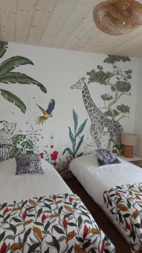 a bedroom with two beds and a mural of a giraffe at LE NID DES PLANCHETTES - Suite Chambres d'Hôtes in Germéfontaine