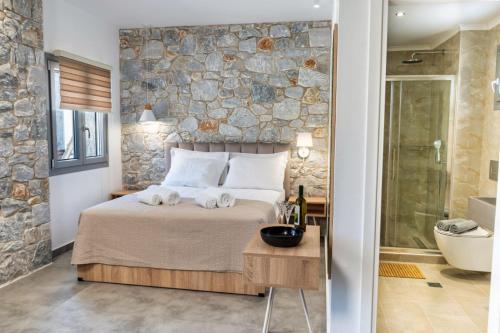 um quarto com uma cama e uma parede de pedra em THALASSIA LUXURY APARTMENTS em Stavros