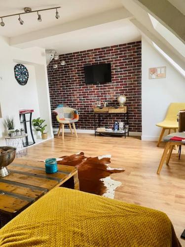 a living room with a brick wall and a tv at L idylle de Guillaume in Falaise