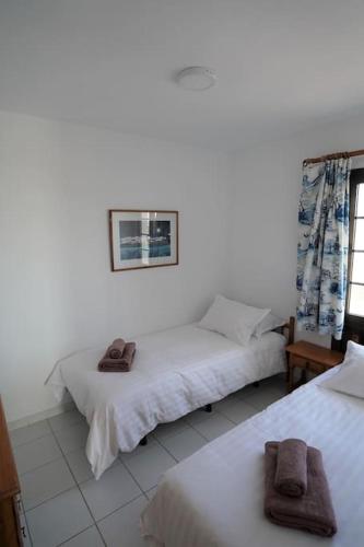 two beds in a white room with towels on them at El Caleton Sea View Apartment in El Cotillo
