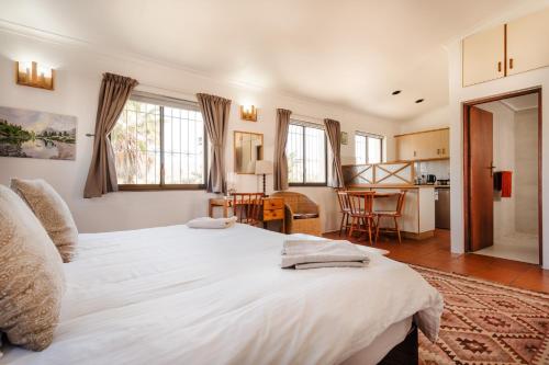 a bedroom with a large white bed and a kitchen at Vlei Cove in Cape Town