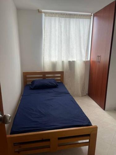 a bedroom with a bed with a blue blanket and a window at Apartamento bien ubicado. in Bucaramanga