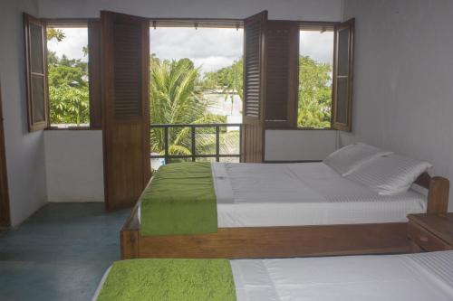 a bedroom with two beds and a balcony with windows at Waira Selva Hotel in Puerto Nariño
