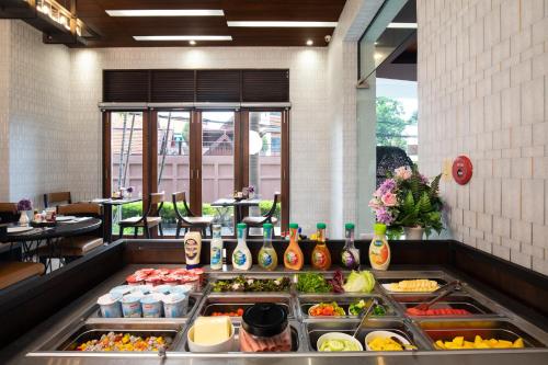 una línea de buffet en un restaurante con muchas comidas diferentes en De Chai Colonial Hotel & Spa - SHA Plus, en Chiang Mai