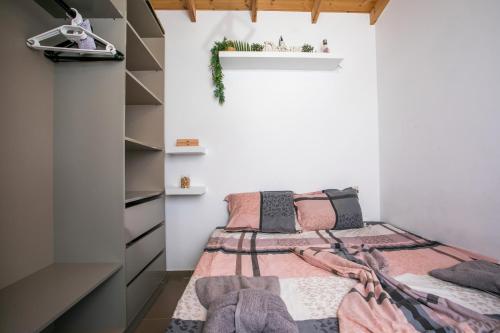 a bedroom with a bed with pink and grey blankets at Marco Beach Tiny House in Faliraki