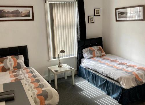 a bedroom with two beds and a table and a window at The Hotel Blackpool in Blackpool