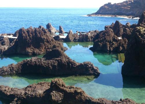 a bunch of rocks in the ocean with water at Villa Vista Norte in Porto Moniz