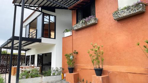 an orange and white building with potted plants on it at Aguas Claras Luxury Hospedaje in Filandia