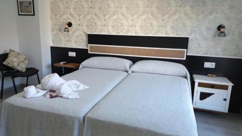 1 dormitorio con 2 camas y toallas blancas. en Lar ABEANCOS, en Melide
