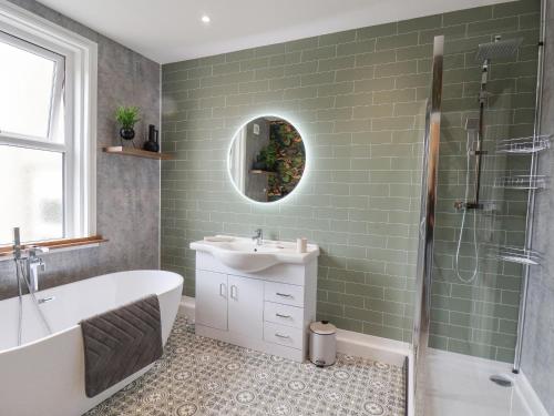 uma casa de banho com uma banheira, um lavatório e um espelho. em 3 Auborough Street em Scarborough