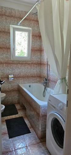 a bathroom with a tub and a washing machine at Holiday Apartment Arman in Vižinada