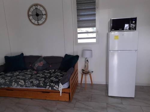 a living room with a couch and a clock on the wall at Bungalow agéable et confortable, parking securisé in Vieux-Habitants