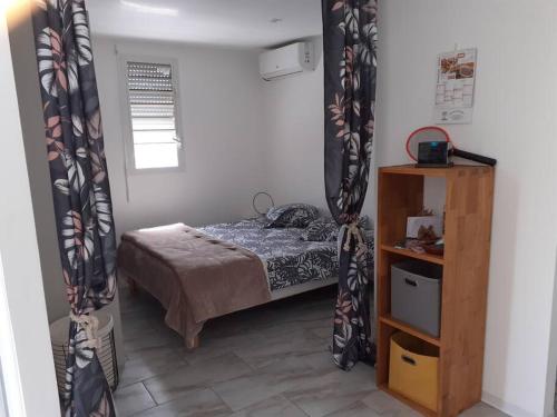 een slaapkamer met een bed in een kamer met gordijnen bij Bungalow agéable et confortable, parking securisé in Vieux-Habitants
