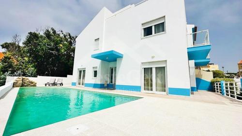 a villa with a swimming pool in front of a house at Santa Efigênia in Lourinhã