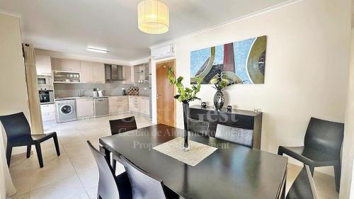 a dining room and kitchen with a black table and chairs at Santa Efigênia in Lourinhã