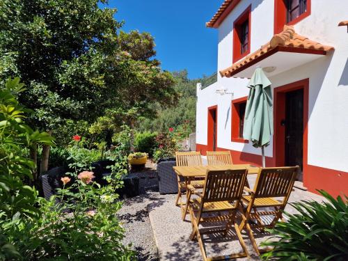 uma mesa de madeira e cadeiras fora de uma casa em Cantinho Rural em Camacha