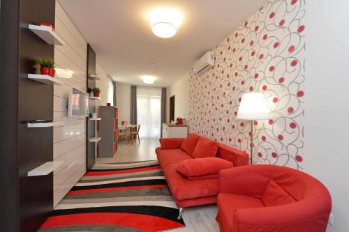 a living room with two red chairs and a wall at Aranymandula apartmanok in Balatonakali