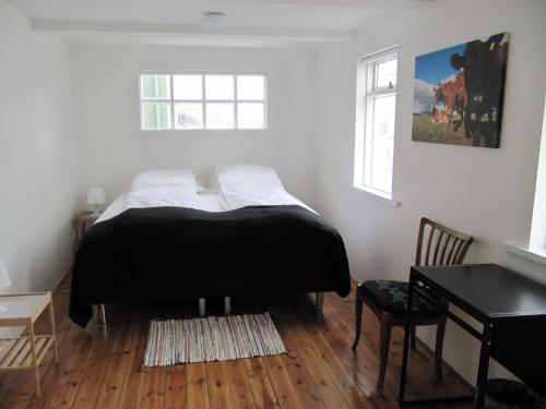 a bedroom with a bed and a table and a desk at Grand-Inn Bar and Bed in Sauðárkrókur