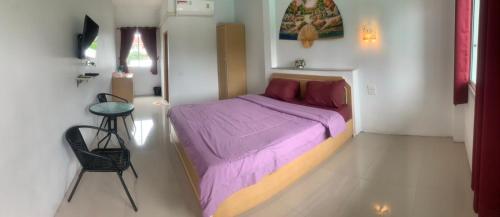 - une petite chambre avec un lit violet et une chaise dans l'établissement บ้านพักณัฐรินีย์, à Sam Phran