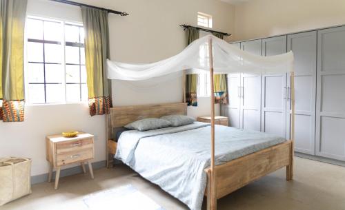 sypialnia z łóżkiem z baldachimem w obiekcie JINJA HOUSE w mieście Jinja