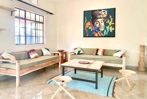 ein Wohnzimmer mit 2 Sofas und einem Tisch in der Unterkunft JINJA HOUSE in Jinja