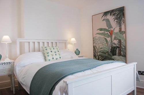 陶因的住宿－Driftwood Designer Apartment，卧室配有白色的床和墙上的绘画作品