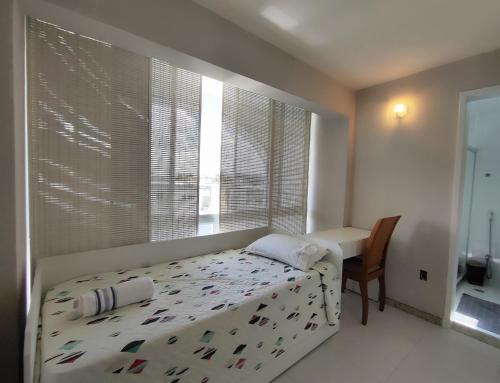 Schlafzimmer mit einem Bett, einem Schreibtisch und einem Fenster in der Unterkunft Aluguel temporada em Vilas do Atlantico a 2 minutos da praia in Lauro de Freitas