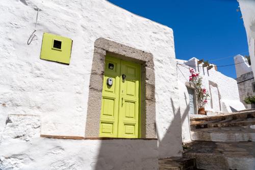 żółte drzwi na białym budynku ze schodami w obiekcie Vintage White House Patmos w mieście Patmos