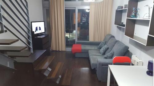 Ático,loft ,duplex في مدريد: غرفة معيشة مع أريكة رمادية وكرسي احمر