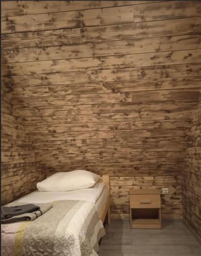 a bedroom with a bed and a wooden wall at Rajskie wzgórze w Karkonoszach in Łomnica