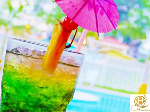 a drink with a pink straw and an umbrella at Hotel Las Hamacas in La Ceiba