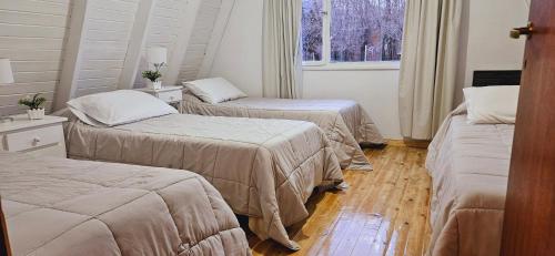 Cette chambre comprend 2 lits et une fenêtre. dans l'établissement La Alpina, à El Calafate