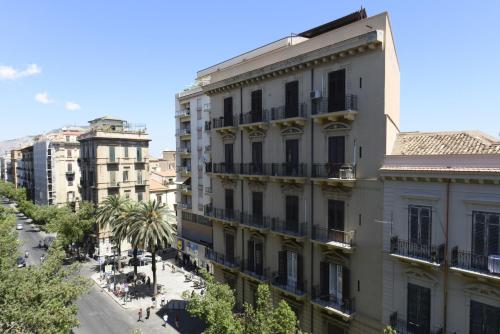 un edificio en una ciudad con una calle y palmeras en Hotel Roma 62, en Palermo