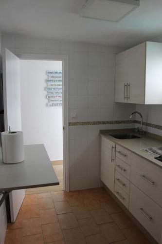 una cocina con armarios blancos y fregadero en Alojamiento Teja, en Arcos de la Frontera