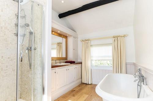a white bathroom with a tub and a shower at Wixey House in Chipping Campden