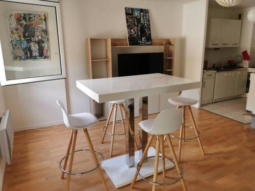 une cuisine avec une table blanche et quatre tabourets dans l'établissement Plage du Havre, au Havre