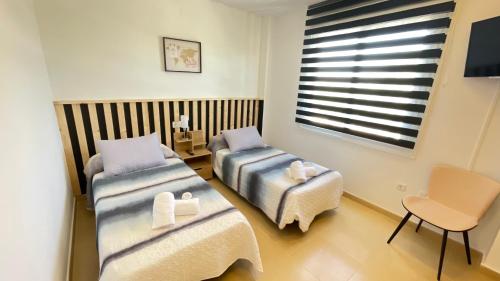 Cette chambre dispose de deux lits, d'une chaise et d'une fenêtre. dans l'établissement Apartamento golf-resort murcia, à Murcie