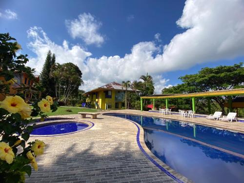 a pool at a resort with tables and chairs at Ecohotel La Casona in Pereira