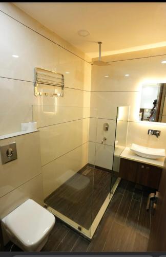 Un baño con ducha, inodoro y lavabo. en Cyber Vista, en Gurgaon