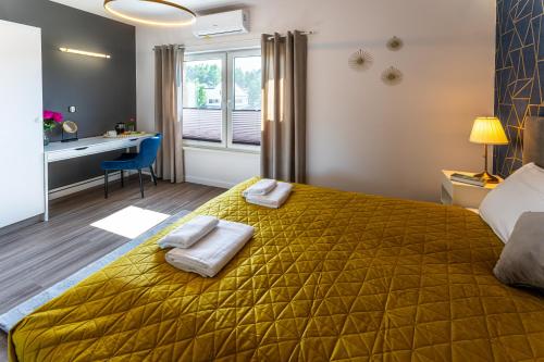 a bedroom with a yellow bed with two towels on it at Klif Resort Apartamenty in Mechelinki