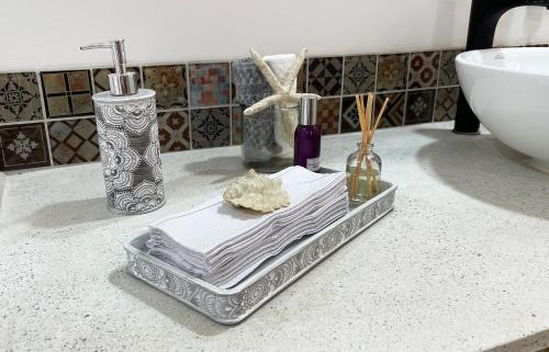 un bancone del bagno con vassoio, asciugamani e lavandino di Aguas Claras Luxury Hospedaje a Filandia