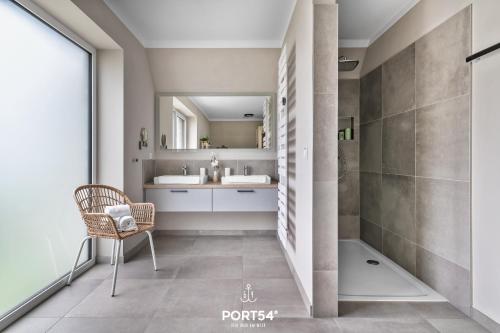 uma casa de banho com um lavatório, um chuveiro e uma cadeira. em Korn-Koje em Büsum