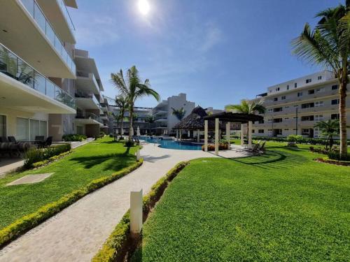 a resort yard with a swimming pool and palm trees at Depto en Diamante con Club de Playa Privado in Acapulco