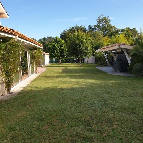 einen Hof neben einem Haus mit großem Rasen in der Unterkunft Chambre 2 in La Brede