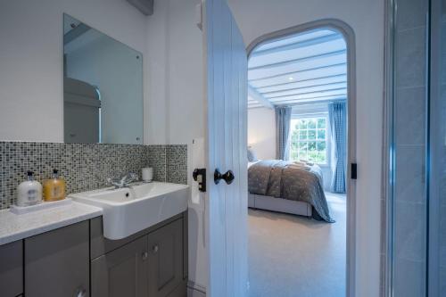 a bathroom with a sink and a mirror and a bedroom at Vine Cottage in Halford